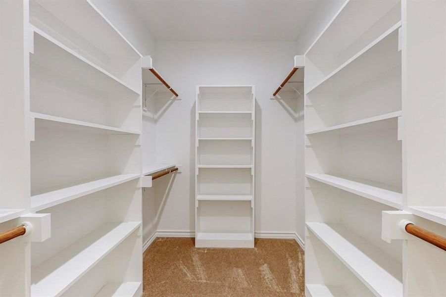 Primary Bedroom Walk in closet with light colored carpet