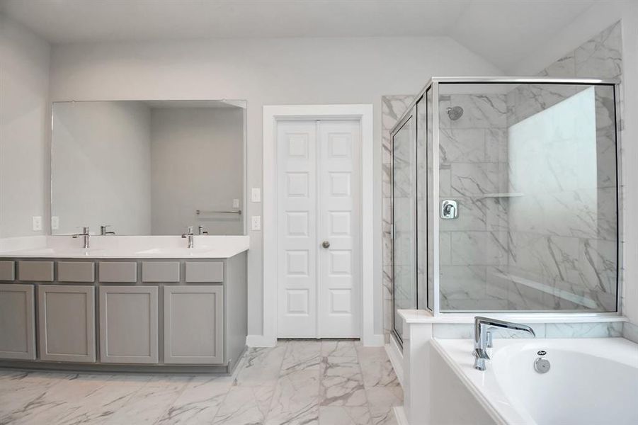 Escape to a spa-like oasis in this primary bathroom. Enjoy a walk-in shower with tile surround, a separate garden tub with custom detailing, and an elegant vanity featuring light countertops, modern hardware, and recessed lighting. Experience luxury and relaxation in every detail.