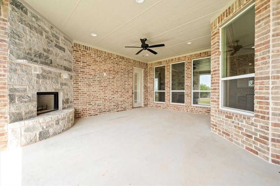 View of patio featuring an outdoor stone fireplace and ceiling fan