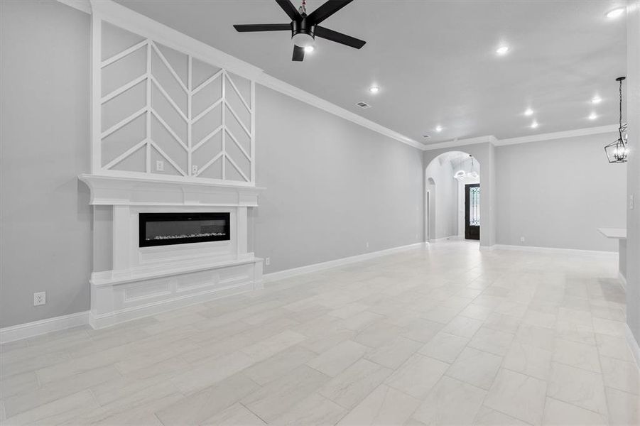 Unfurnished living room featuring crown molding, a fireplace, and ceiling fan