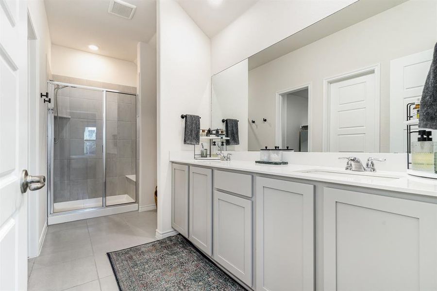 Bathroom featuring a shower with door, vanity, and tile patterned flooring