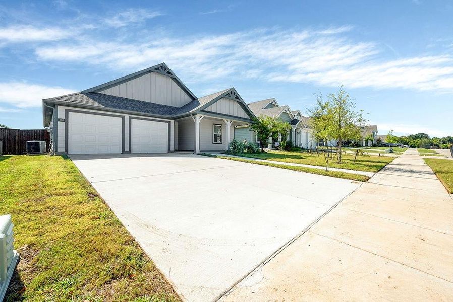 View of front of home featuring a garage, central AC unit, and a front yard