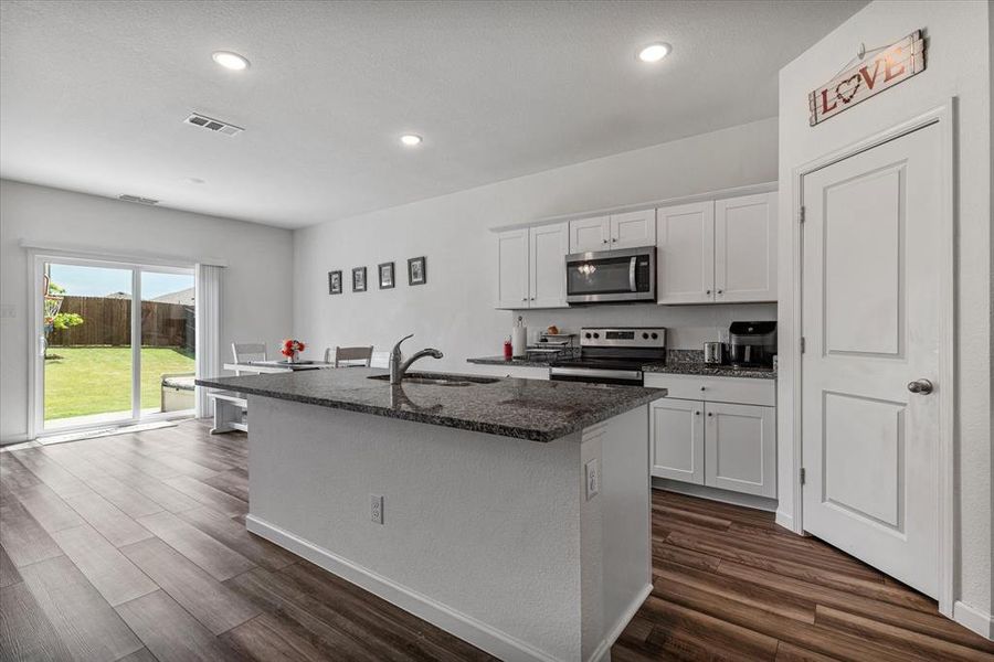 Kitchen featuring appliances with stainless steel finishes, hardwood / wood-style floors, white cabinets, and sink