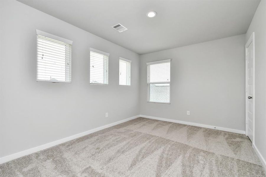 Secondary bedroom. Plush carpet, neutral paint color, large windows, and spacious closets.