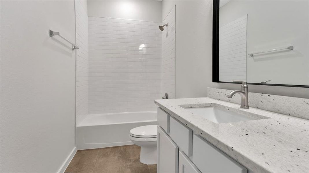 Full bathroom featuring hardwood / wood-style floors, vanity, toilet, and tiled shower / bath