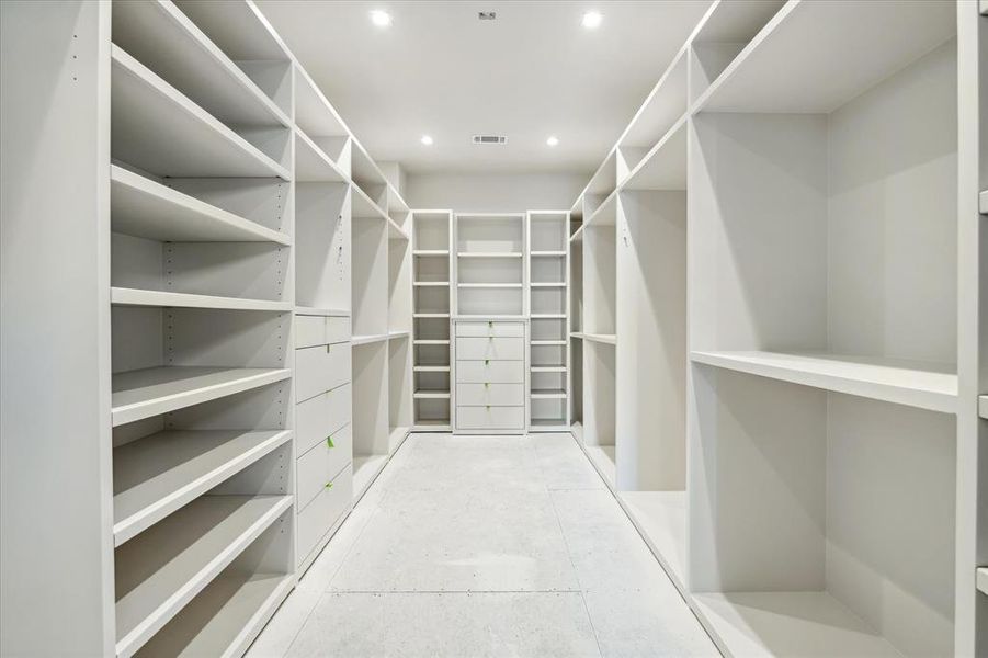 The primary closet offers an abundance of hanging space, drawers, and custom-built display and shoe shelves.