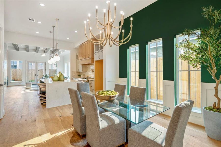 As you walk into the home, a formal dining space with ample natural light under a custom chandelier. Notice a seamless open-concept floor plan flowing into your island kitchen and living room. 12 foot ceilings span entire first floor.
