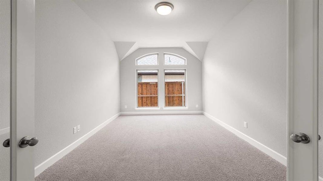 Carpeted spare room with lofted ceiling