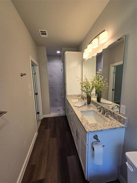 Bathroom featuring vanity, hardwood / wood-style floors, an enclosed shower, and toilet