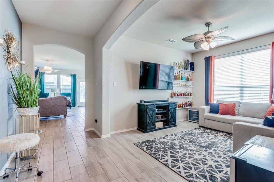 Living room featuring ceiling fan, bar area, and light hardwood / wood-style floors