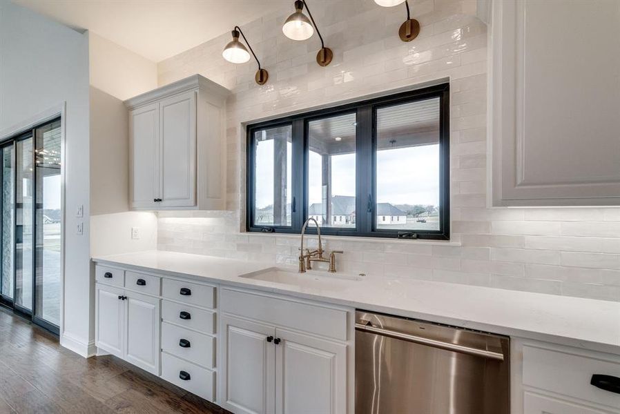 Kitchen with sink, decorative backsplash, dark hardwood / wood-style floors, stainless steel dishwasher, and white cabinetry