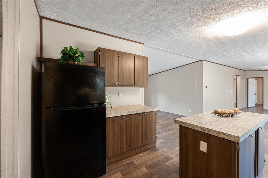 Kitchen featuring black fridge, dark hardwood / wood-style flooring, and a textured ceiling