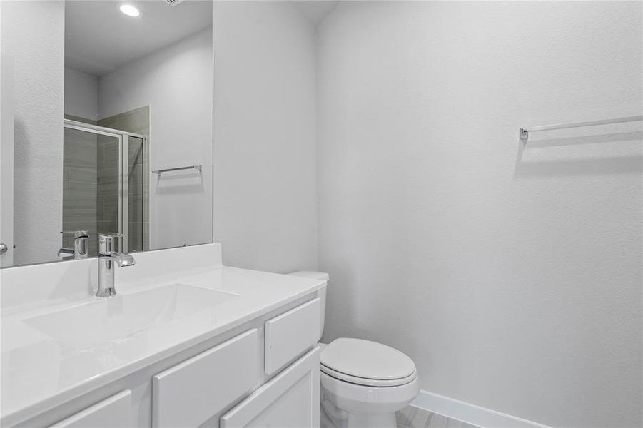 This secondary bath has private access to the front secondary bedroom. It features tile flooring, shower with tile surround, white stained wood cabinets, beautiful light countertops, mirror, sleek fixtures and modern finishes.