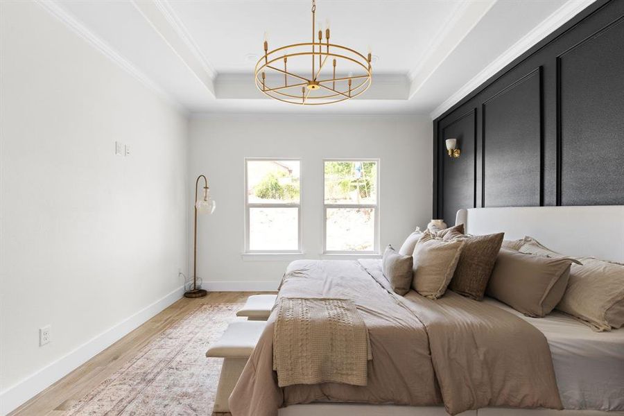 Bedroom with crown molding, a raised ceiling, a chandelier, and light hardwood / wood-style floors