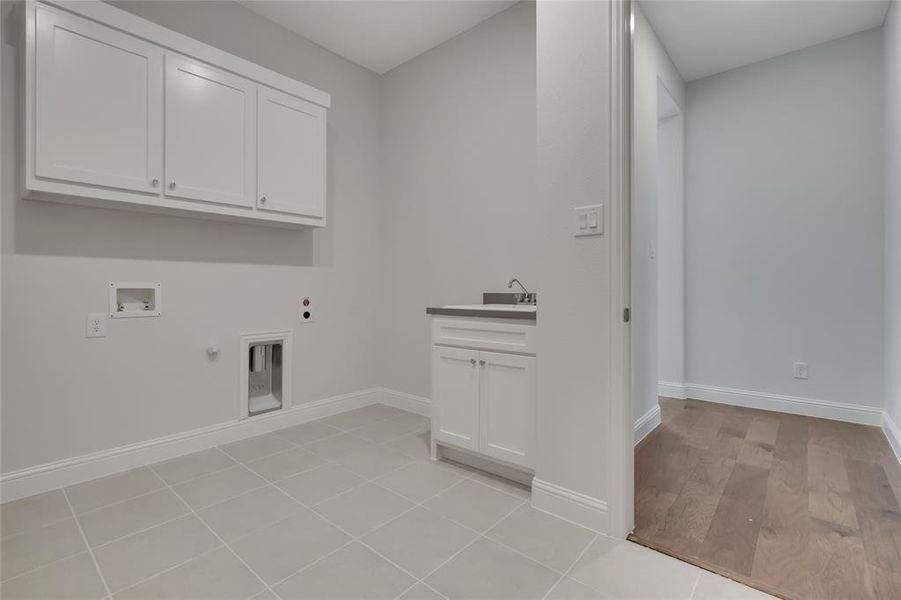 Clothes washing area with light hardwood / wood-style flooring, washer hookup, cabinets, hookup for an electric dryer, and gas dryer hookup