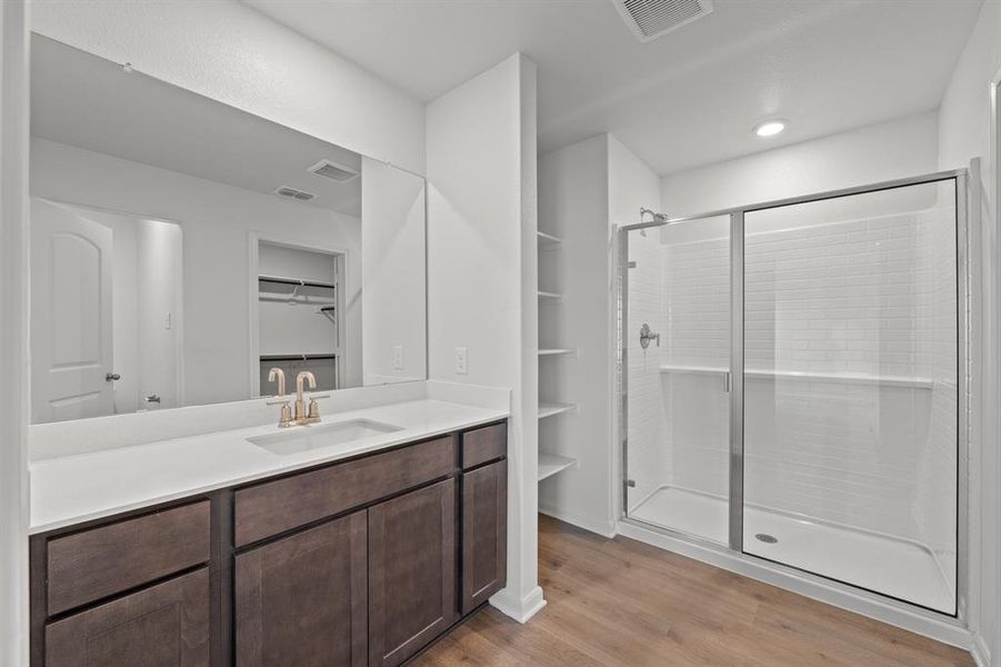 Bathroom featuring wood-type flooring, a shower with door, and vanity