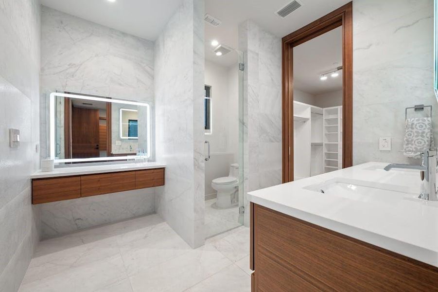 The main bathroom vanity area exudes elegance and functionality. Featuring a sleek, modern design, it includes a spacious countertop, dual sinks, and ample storage. The high-quality finishes and well-placed lighting enhance the sophisticated atmosphere, making it a perfect blend of style and practicality.