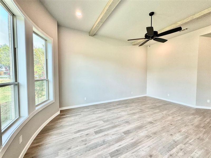 Primary room featuring ceiling fan, a wealth of natural light, beam ceiling, and light hardwood / wood-style flooring