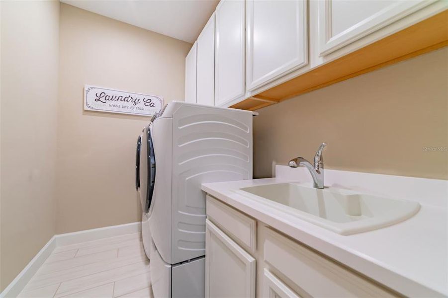 Laundry room includes extra cabinetry and front load washer/dryer