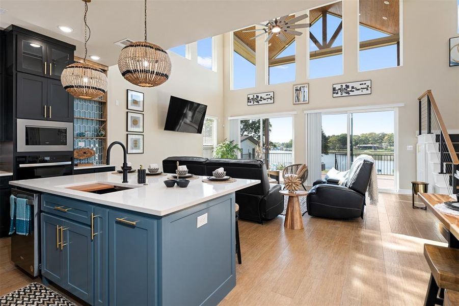 Kitchen with black oven, blue cabinetry, sink, a chandelier, and a kitchen island with sink