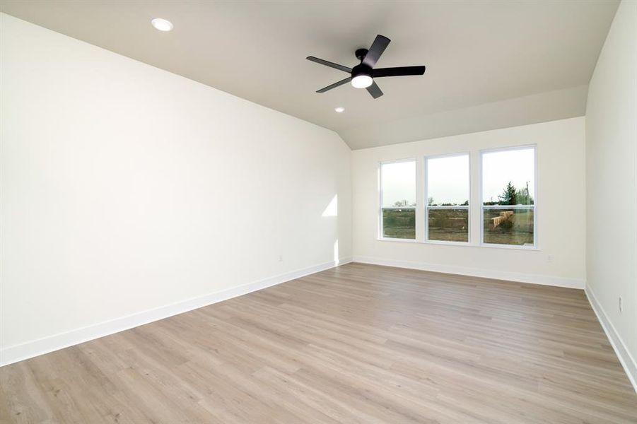 Empty room with ceiling fan, vaulted ceiling, and light hardwood / wood-style flooring