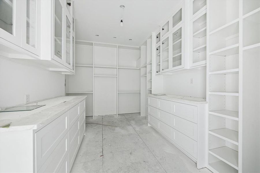 An outstanding primary closet in the making.  Adjustable shelving throughout, an abundance of drawers and soon to come, pull-down rod systems and glass-front cabinetry make this space the ultimate in organization and enjoyment.  The primary closet also offers access to the second floor utility room.  Photo as of 9/3/2024