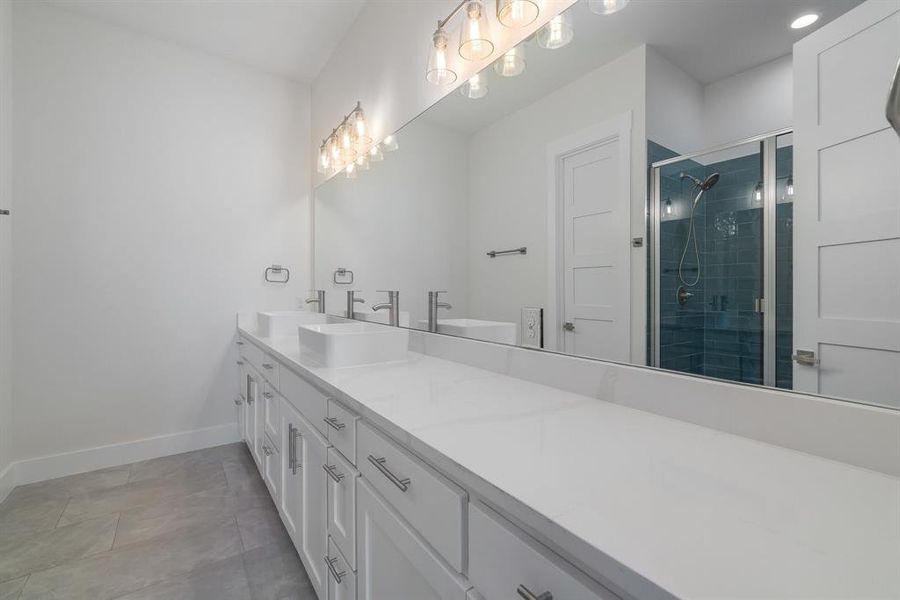 Bathroom with double vanity, an enclosed shower, and tile patterned flooring