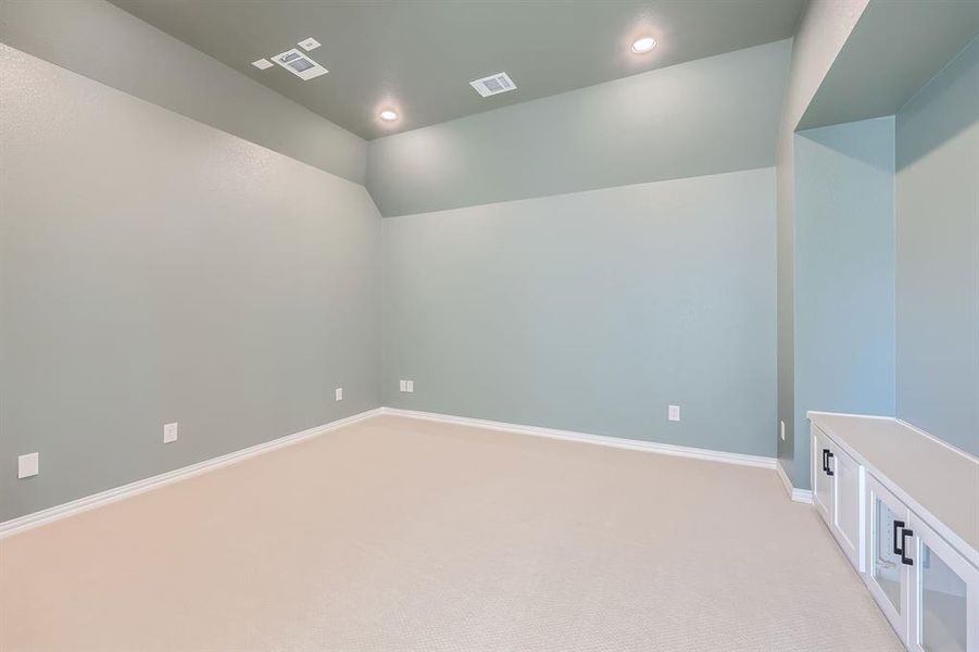 Empty room with light carpet and lofted ceiling