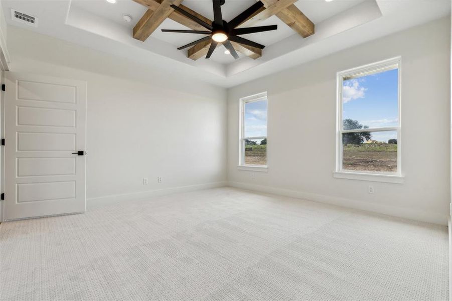 Carpeted spare room featuring coffered ceiling, beam ceiling, and ceiling fan