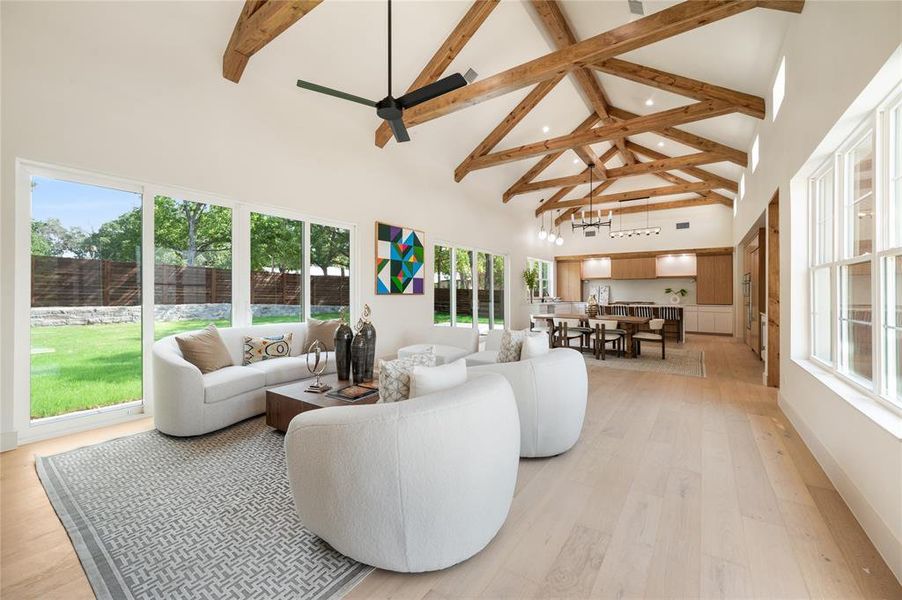 Living room featuring beamed ceiling, high vaulted ceiling, a healthy amount of sunlight, and light wood-type flooring