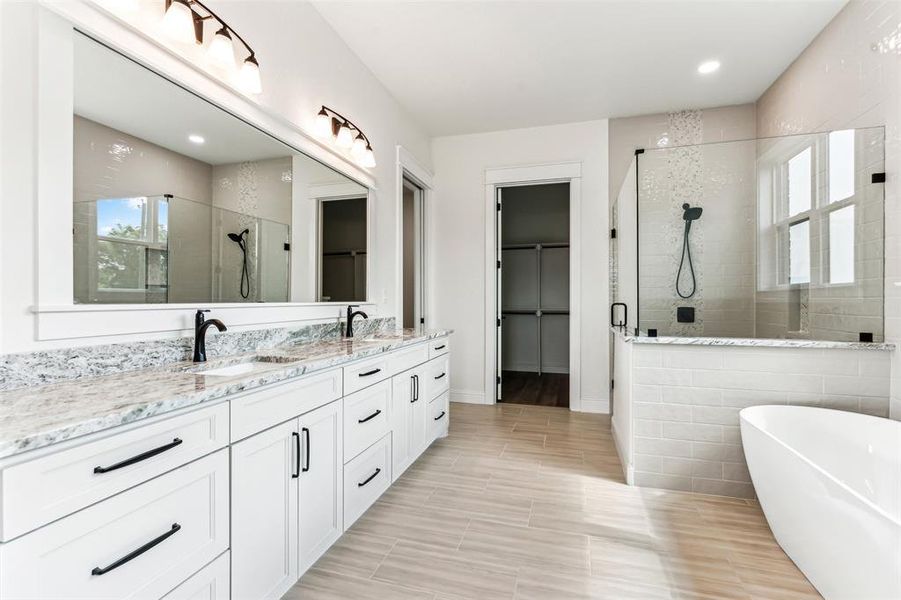 Primary Bathroom with independent shower and bath, dual vanity, tile patterned flooring, and tile walls