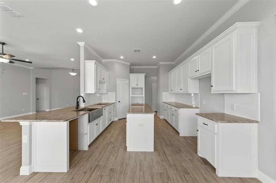 Kitchen featuring light stone countertops, a kitchen island, kitchen peninsula, white cabinetry, and light hardwood / wood-style flooring