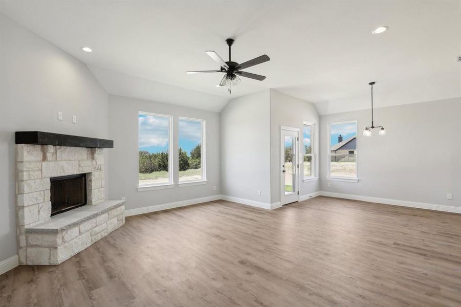 Unfurnished living room featuring a fireplace, ceiling fan, hardwood / wood-style floors, and lofted ceiling