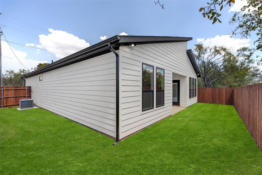 View of property exterior with central air condition unit and a lawn