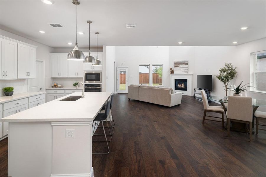 Kitchen featuring white cabinets, appliances with stainless steel finishes, sink, dark wood-type flooring, and a kitchen island with sink