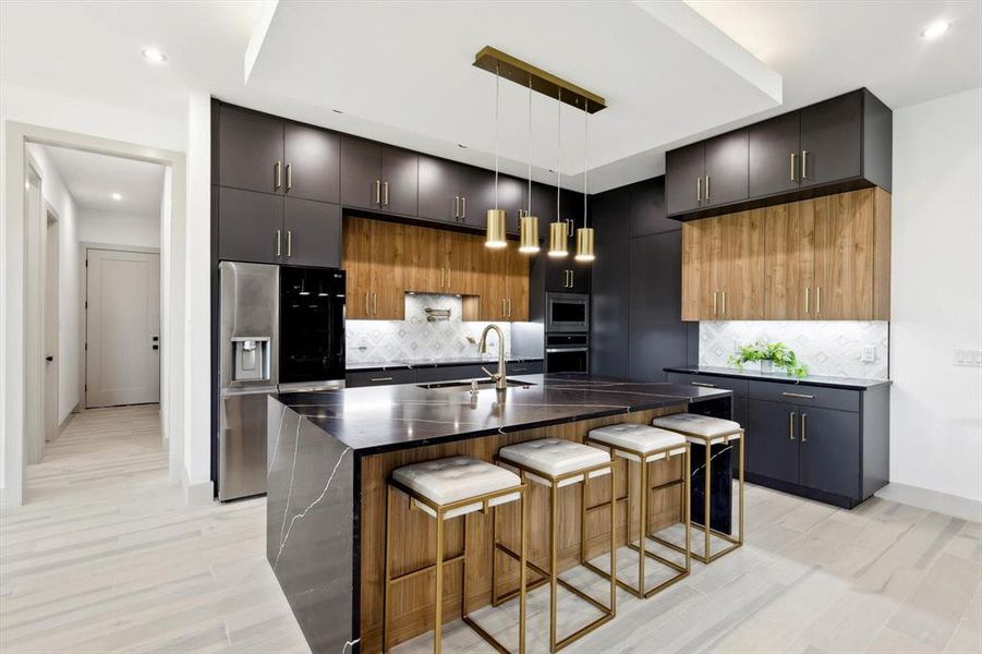 Kitchen with decorative backsplash, sink, a breakfast bar area, appliances with stainless steel finishes, and a kitchen island with sink
