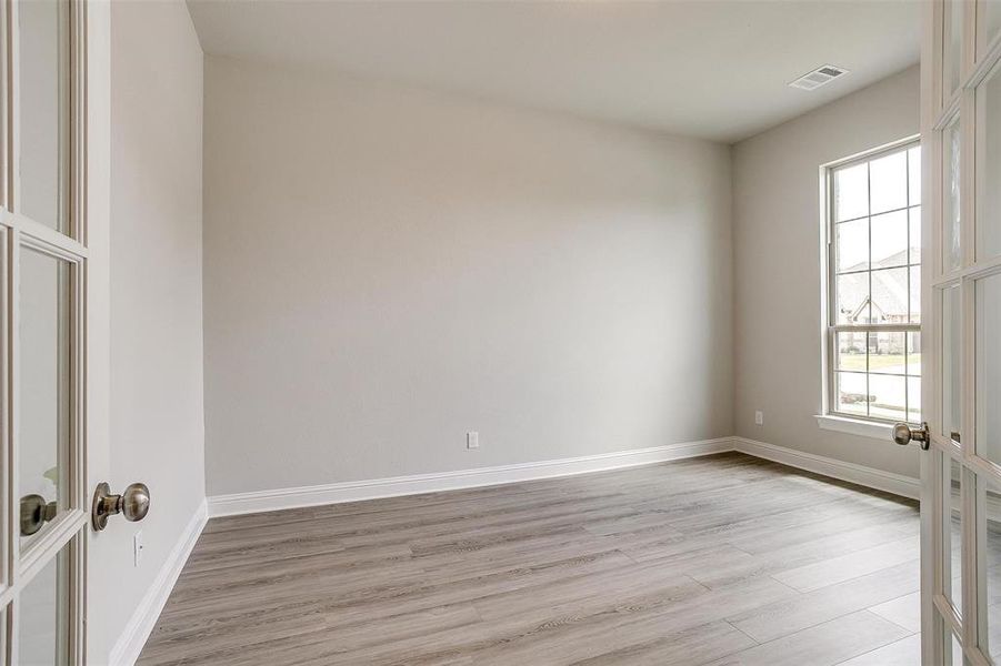 Empty room with light hardwood / wood-style flooring and french doors