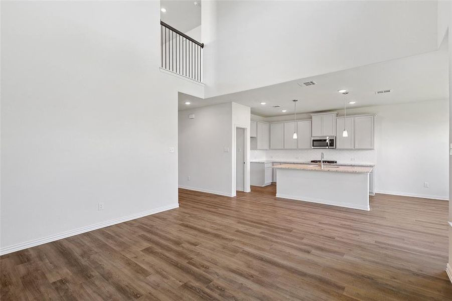 Unfurnished living room featuring a high ceiling and wood-type flooring