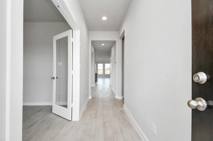 The grand entrance beckons with its soaring ceilings, adorned with elegant wood-look tile flooring featuring sleek oversized baseboards. Photo shown is example of completed home with similar plan.