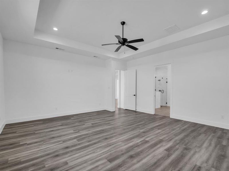 Spare room with hardwood / wood-style flooring, a tray ceiling, and ceiling fan