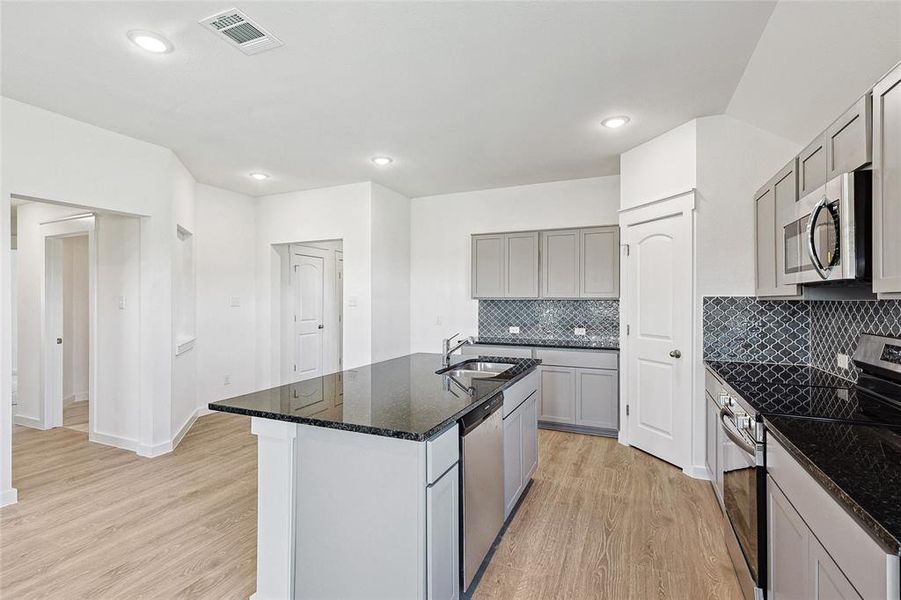 Kitchen featuring light wood-type flooring, appliances with stainless steel finishes, gray cabinets, and sink