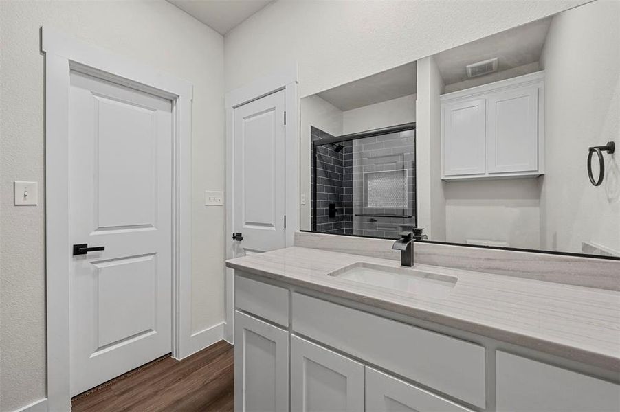 Bathroom with wood-type flooring, a tile shower, and vanity