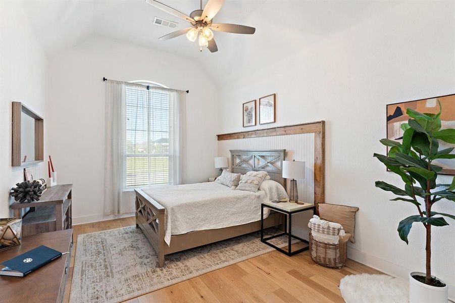 Bedroom featuring lofted ceiling, ceiling fan, a fireplace, and light hardwood / wood-style floors