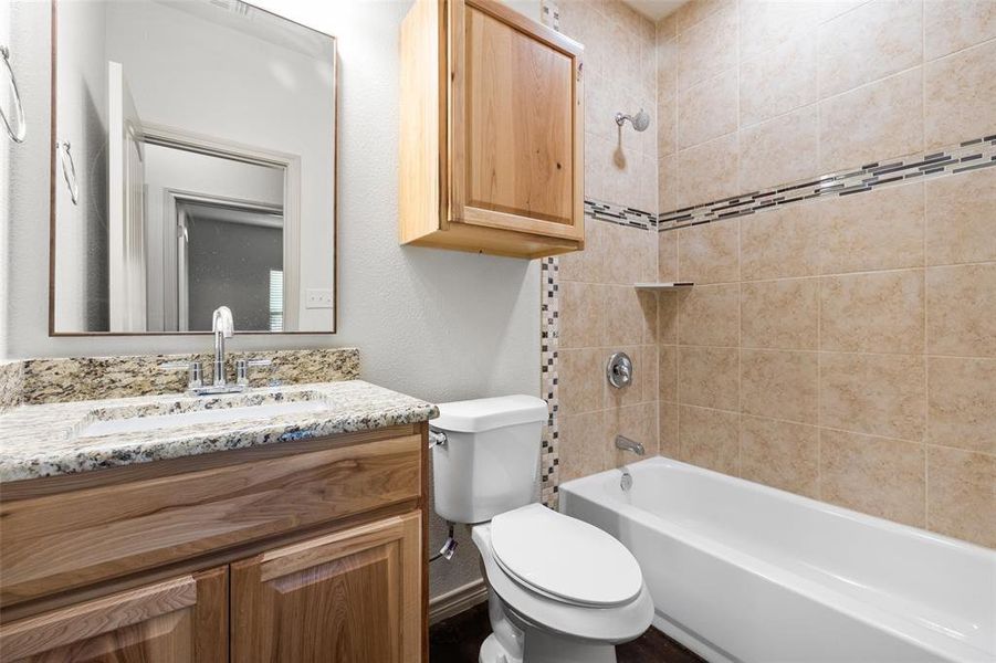 Full bathroom with vanity, tiled shower / bath, and toilet