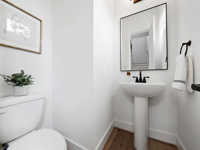 The powder room located on the second floor by the stairs showcases it's own style with matte fixture and faucets.