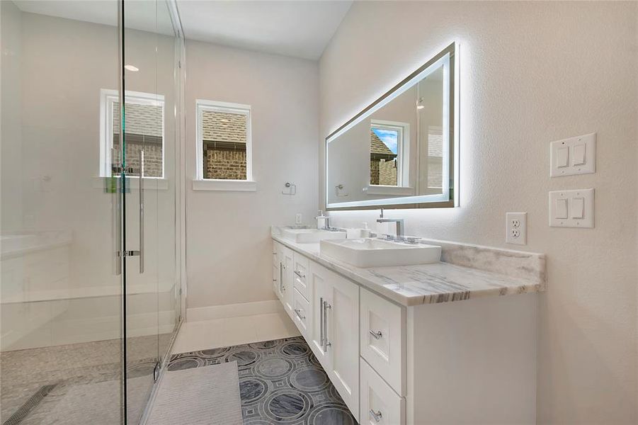Bathroom with dual vanity, plenty of natural light, tile flooring, and a shower with door