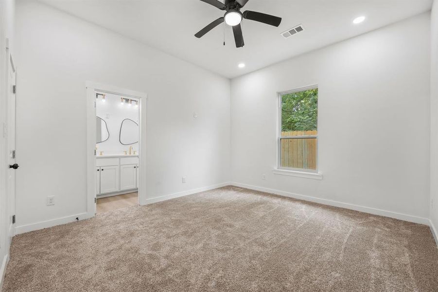 Unfurnished bedroom with light carpet, ceiling fan, and connected bathroom