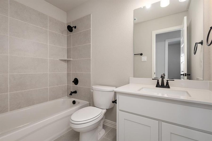 Full bathroom featuring vanity, toilet, tile patterned flooring, and tiled shower / bath