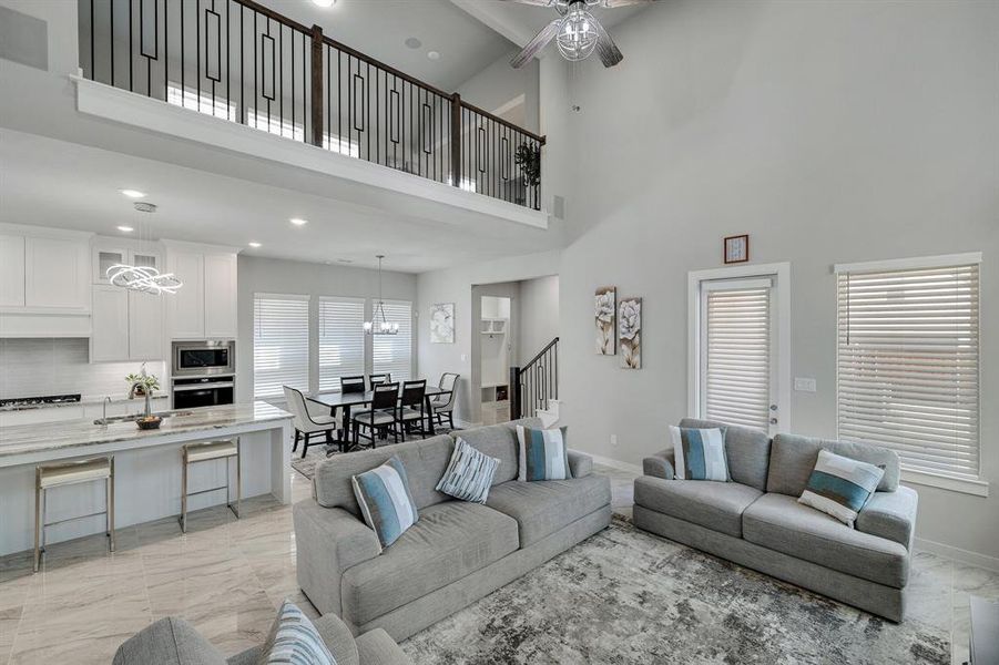 Living room with a wealth of natural light, light tile patterned floors, and a high ceiling