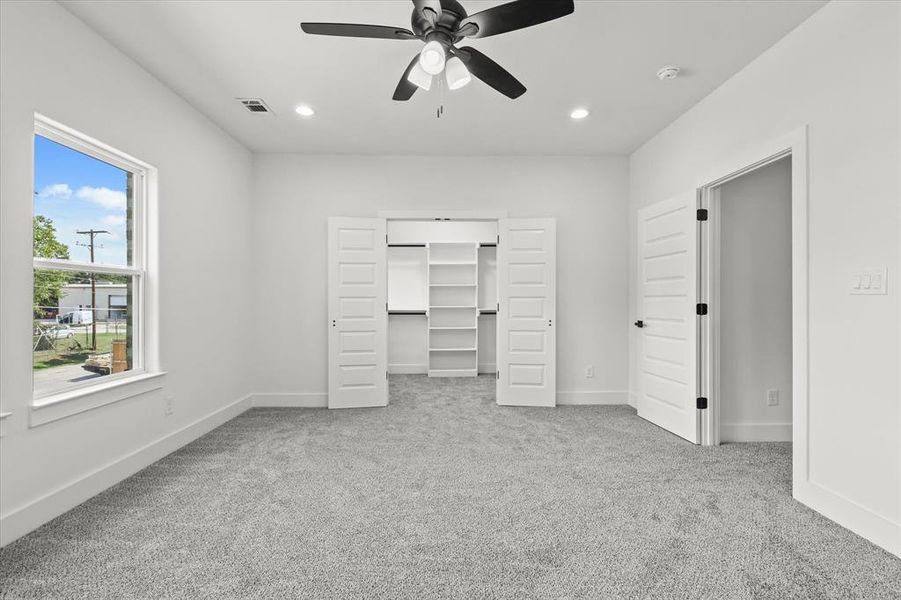 Unfurnished bedroom featuring light colored carpet, ceiling fan, a spacious closet, and a closet